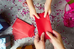 Close up hands of parent giving a red envelope or money red packet to child  .  Chinese new year and Lunar new year festival concept background . Top view .