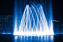 Beautiful fountain at night illuminated with blue light.