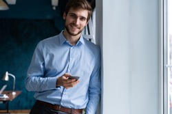 handsome young bearded business man in office using mobile phone indoors
