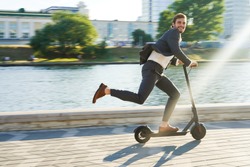 Young business man in a suit riding an electric scooter on a business meeting. Ecological transportation concept