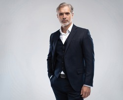 Handsome middle-aged man in suit posing against grey background