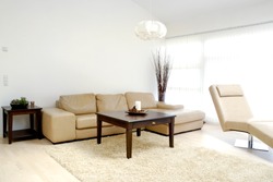 A modern living room with table, sofa and armchair.