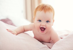 happy excited infant baby girl crawling on the bed