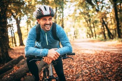 Professional mountain bike cyclist riding trail in forest, details of sports. Toothy smile.