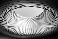 Black and white color and tone, Close up detail of circular architectural shape with woven pattern aluminium panel facade and a big hole on the centre. Messe Basel in Switzerland.