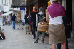 Low angle and selected focus, European people queue and wait for shopping on sidewalk outside supermarket during quarantine for COVID-19 virus in Düsseldorf, Germany.