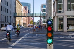 Selective focus, Green traffic light with bicycle symbol on sidewalk beside bicycle lane in Europe and defocus of people ride bicycle.