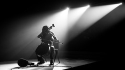 Silhouette cello player perform on stage with spotlight in monochrome,noise added
