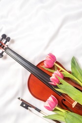 Acoustic violin and red tulips on white silk blanket. High quality photo