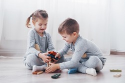 Children play with a toy designer on the floor of the children's room. Two kids playing with colorful blocks. Kindergarten educational games.