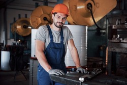 Portrait of a young worker in a hard hat at a large metalworking plant. The engineer serves the machines and manufactures parts for gas equipment.