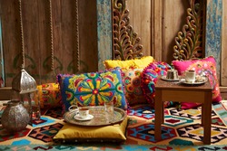 carved wood design pillows embroidered with fluorescent colors in front of the wall oriental corner turkish coffee presentation