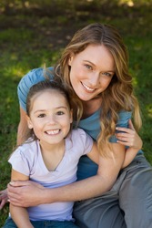 Portrait of a smiling mother embracing her daughter at the park