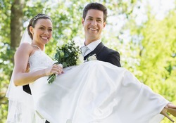 Happy groom carrying bride while looking away in garden