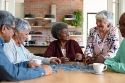 Group of diverse senior male and female friends doing puzzles at home. socialising with friends at home.