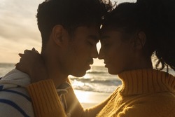 Side view of multiracial couple romancing while hugging each other at beach during sunset. lifestyle, love and weekend.