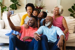 Smiling african american three generation family taking a selfie sitting together on couch at home. family, love and togetherness concept, unaltered.