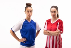 Portrait of biracial and caucasian young female players standing with arms crossed and hands on hip. white background, unaltered, sport, sports uniform, competition, rivalry and women's soccer.