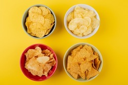Directly above shot of various snacks in bowls on yellow background. unaltered, unhealthy food, snack, variation and salty snack.