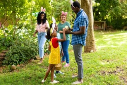 Happy african american siblings wearing bunny ears with family in backyard on easter day. unaltered, lifestyle, easter day, celebration, childhood, cultures and holiday concept.