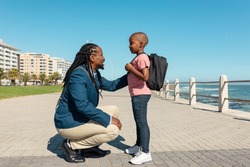 African american father crouching while talking to son with hand on shoulder at promenade. unaltered, parenting, family, lifestyle and togetherness concept.