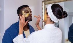 Caucasian young woman applying facial cream on face of boyfriend in bathroom at home. unaltered, lifestyle, togetherness, body care, beauty prdouct, beauty.