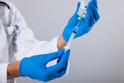 Midsection of african american mid adult female doctor wearing gloves holding vial and syringe. white background, doctor, syringe, vial, treatment, disease, hospital, healthcare, medical occupation.