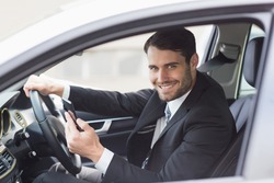 Businessman sending a text message in his car