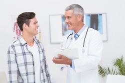 Doctor showing clipboard to his patient in medical office