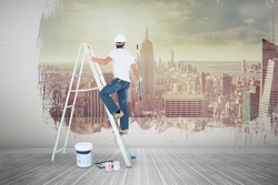 Man on ladder painting with roller against room with large window looking on city