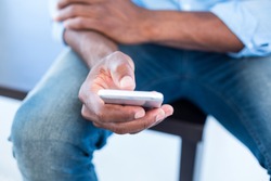 Midsection of man using mobile phone while sitting on bench