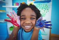 Happy kid enjoying arts and crafts painting with his hands