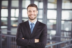 Portrait of happy businessman with arms crossed standing in office
