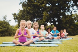 Front view of children doing yoga in the park