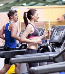 Healthy couple running on a treadmill in a sport centre