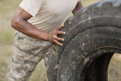 Mid section of military soldiers exercising with tyre in boot camp