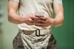 Mid section of military soldier using mobile phone in boot camp