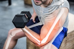 Digital composite of highlighted arm of strong man lifting weights at gym