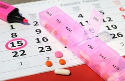 drugs from a pill box on a background of a calendar with a marked date