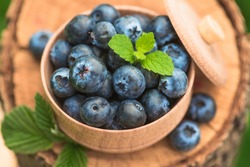Fresh and natural blueberry with mint leaf on a stump green garden background. farming and harvesting berry. top view.