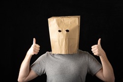 Man wearing a brown paper bag over his head and giving two thumbs up.