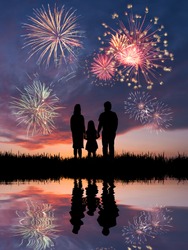 The happy family looks beautiful colorful holiday fireworks in the evening sky with majestic clouds