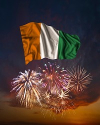 Holiday fireworks in evening sky and flag of Cote d'Ivoire for National Independence day