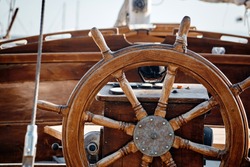 Closeup of a wheel and deck of a wooden antique sailing yacht.