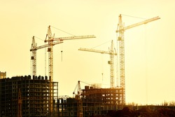 Construction of new residential high-rise buildings. Against the background of a yellow sunset sky.