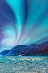 Beautiful landscape cracking ice, frozen norwegian sea coast - Northern lights (Aurora borealis) in the sky over Tromso, Norway