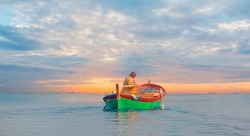 Fisherman with fishing boat in a calm sea in the background amazing sunset