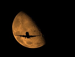 an airplane flying across moon .