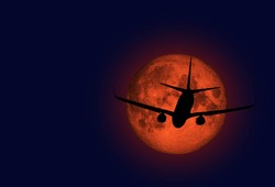 airplane flying across a full moon 