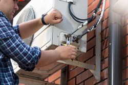 Male technician repairing outdoor air conditioner unit